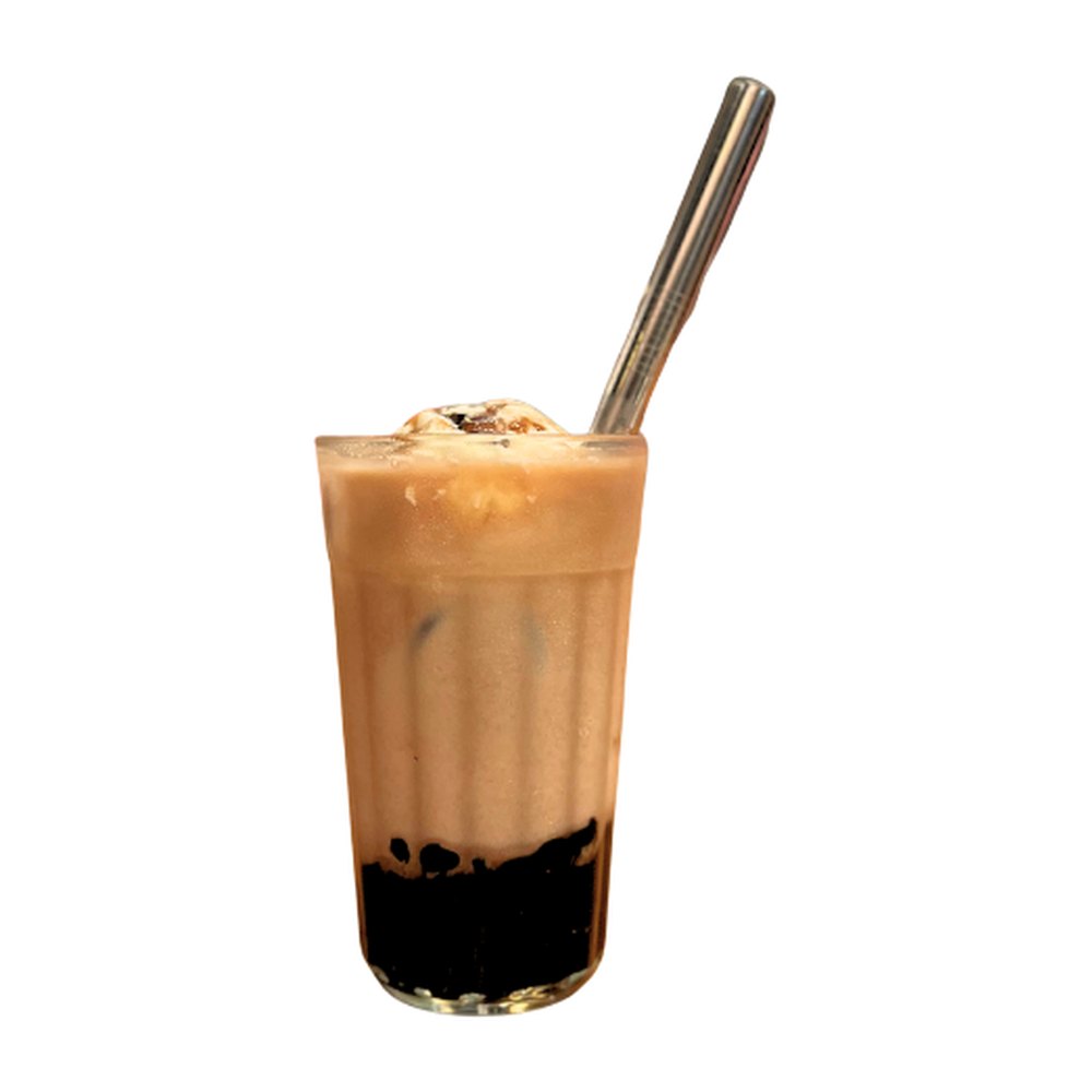 Glass of iced masala chai with dark tapioca pearls at the bottom, ice cream on top and a steel straw