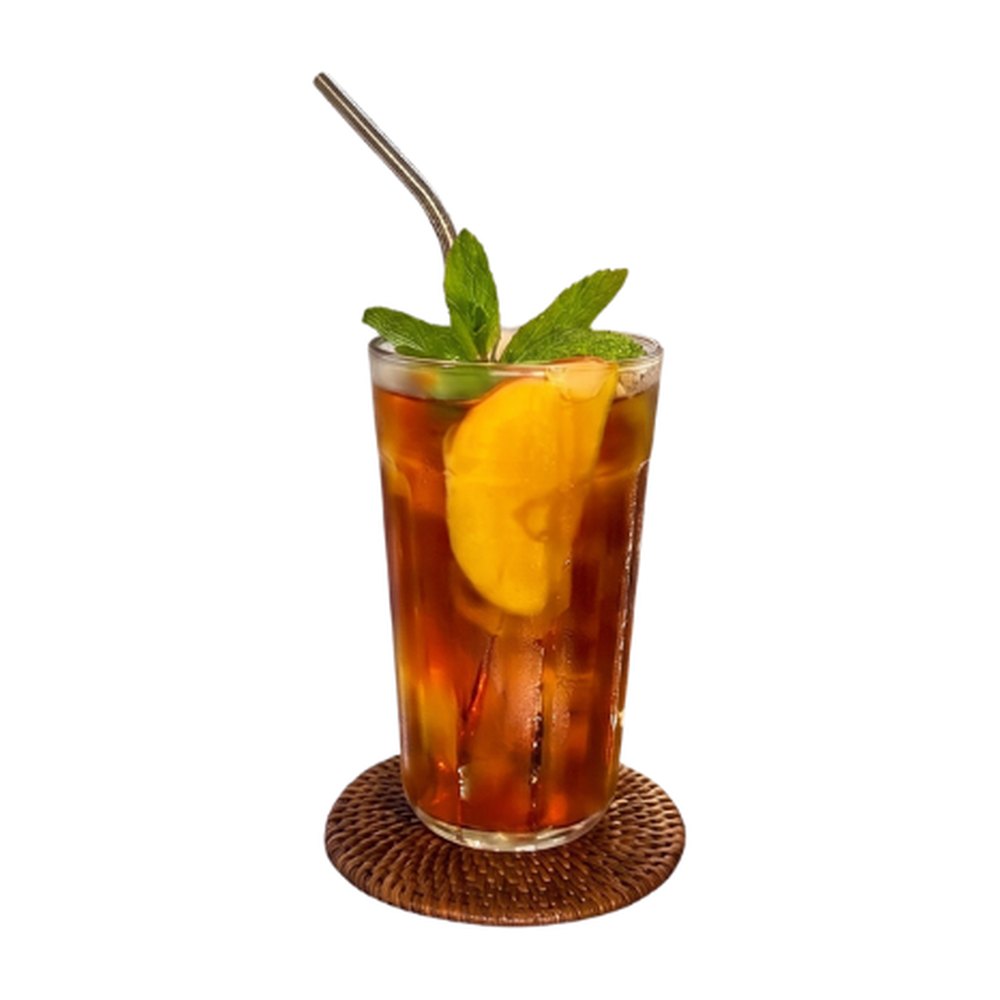 Tall glass of iced rooibos tea with a fruit slice and fresh mint on a rattan coaster